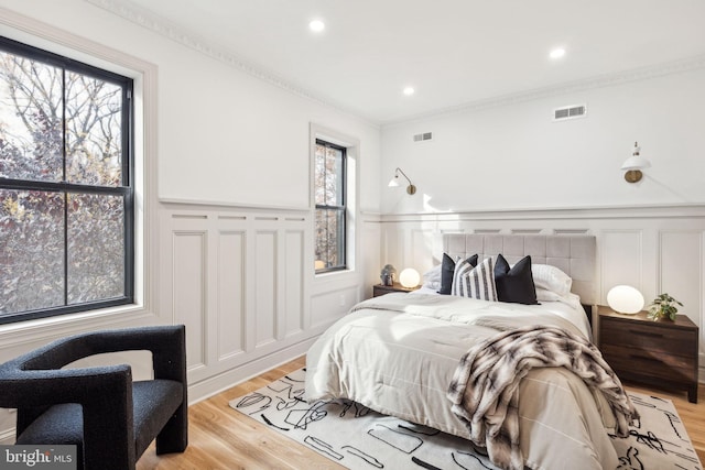 bedroom with ornamental molding and light wood-type flooring