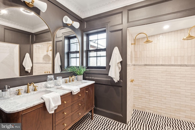 bathroom featuring vanity, ornamental molding, and tiled shower