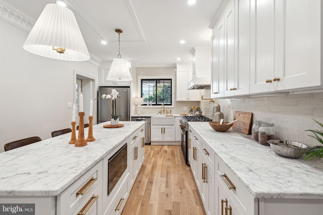 kitchen featuring white cabinetry, light hardwood / wood-style flooring, crown molding, appliances with stainless steel finishes, and custom exhaust hood