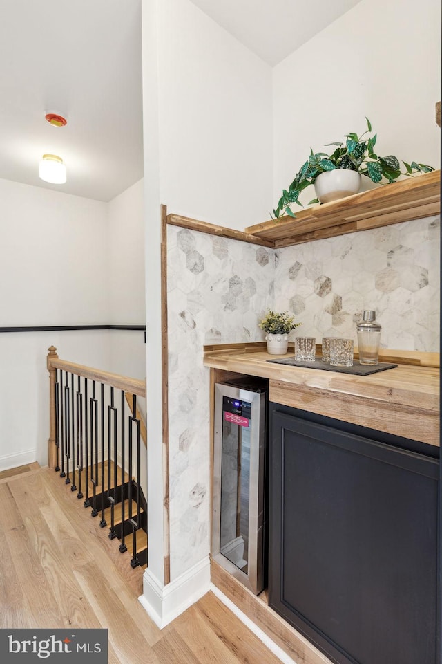 bar with wooden counters, light hardwood / wood-style flooring, and wine cooler