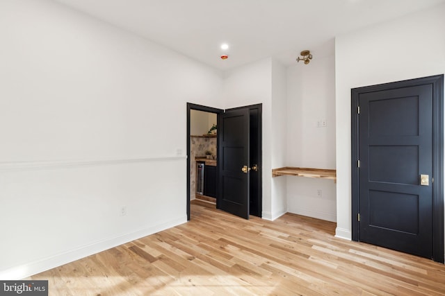 unfurnished bedroom featuring light wood-type flooring and built in desk