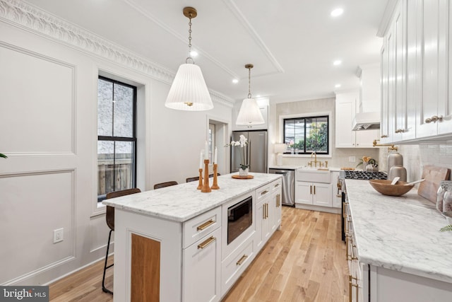 kitchen featuring a center island, light hardwood / wood-style floors, decorative light fixtures, white cabinets, and high end appliances