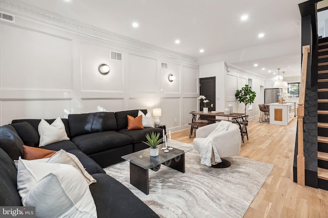 living room featuring crown molding and light hardwood / wood-style flooring