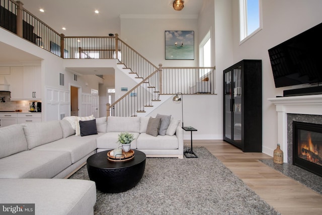 living room with a towering ceiling, a fireplace, and light wood-type flooring