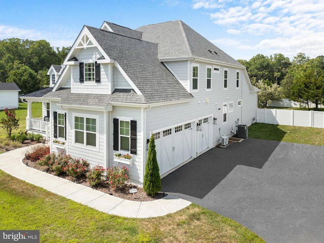 view of front of home with a garage, a front lawn, and central air condition unit