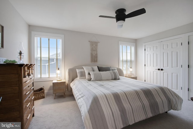 bedroom with ceiling fan, light colored carpet, and a closet