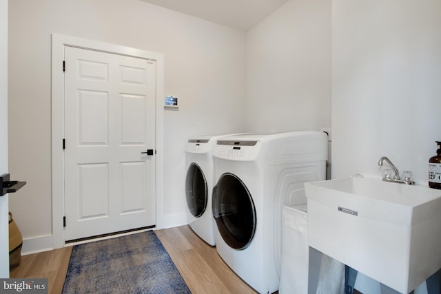 washroom with washing machine and dryer, sink, and light wood-type flooring