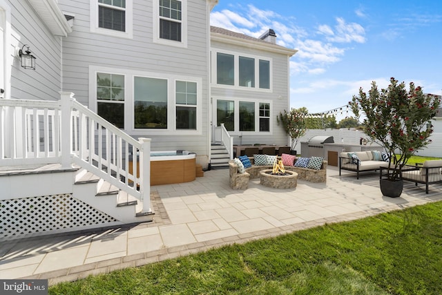 back of property with a hot tub, a patio, and an outdoor living space with a fire pit