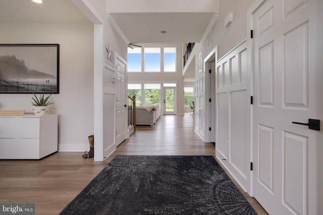 hallway with a towering ceiling and light wood-type flooring