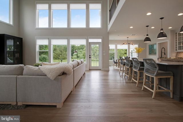 living room with a towering ceiling, a notable chandelier, and light hardwood / wood-style flooring