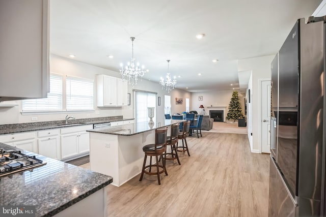 kitchen featuring a kitchen bar, appliances with stainless steel finishes, light hardwood / wood-style flooring, a center island, and white cabinetry