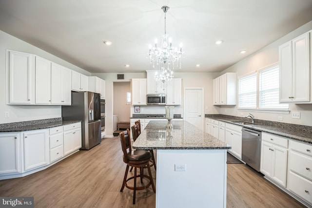 kitchen with a center island, white cabinets, light hardwood / wood-style floors, and appliances with stainless steel finishes