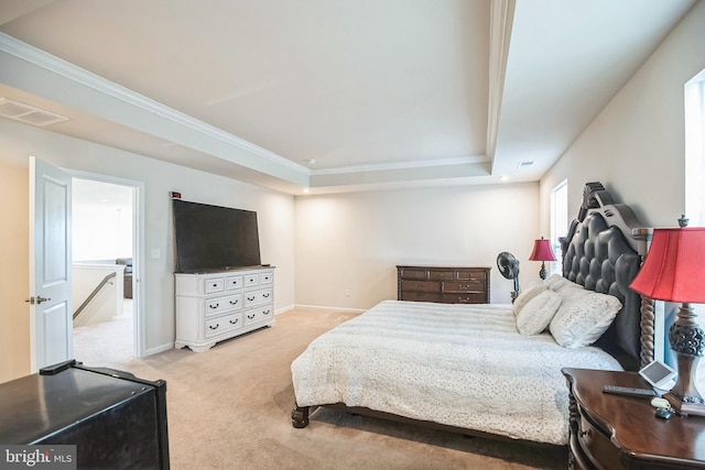 bedroom with a tray ceiling, crown molding, and light colored carpet