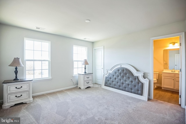 bedroom with sink, light carpet, and connected bathroom