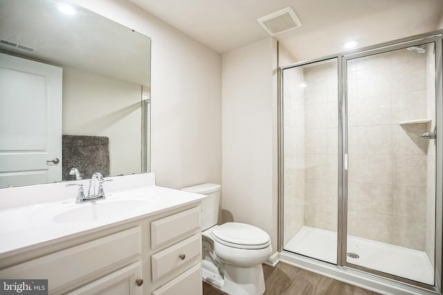 bathroom with hardwood / wood-style floors, vanity, toilet, and a shower with door