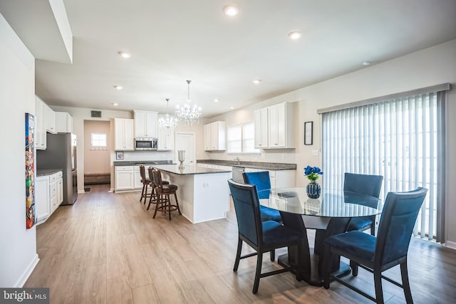 dining room with light hardwood / wood-style flooring and an inviting chandelier