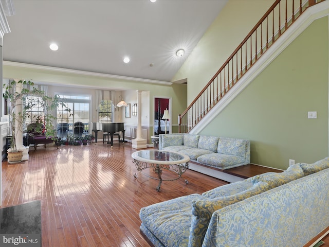 living room with ornate columns, ornamental molding, a high ceiling, and hardwood / wood-style floors