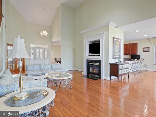 living room featuring high vaulted ceiling, a notable chandelier, and light wood-type flooring