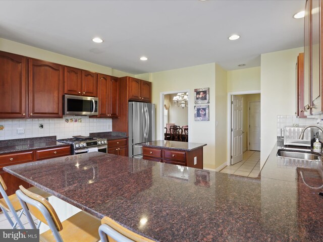 kitchen with a kitchen island, sink, backsplash, a kitchen bar, and stainless steel appliances