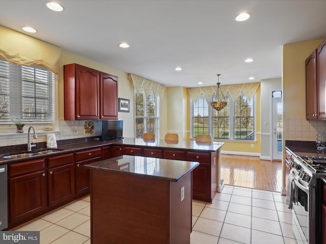 kitchen featuring sink, stainless steel appliances, a kitchen island, decorative light fixtures, and kitchen peninsula