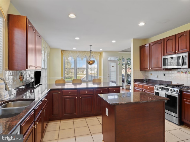 kitchen featuring sink, hanging light fixtures, appliances with stainless steel finishes, kitchen peninsula, and a kitchen island