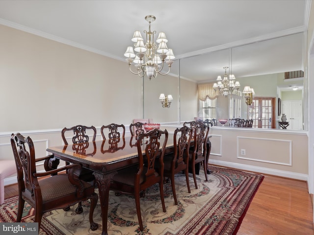 dining space featuring ornamental molding, a notable chandelier, and light hardwood / wood-style flooring