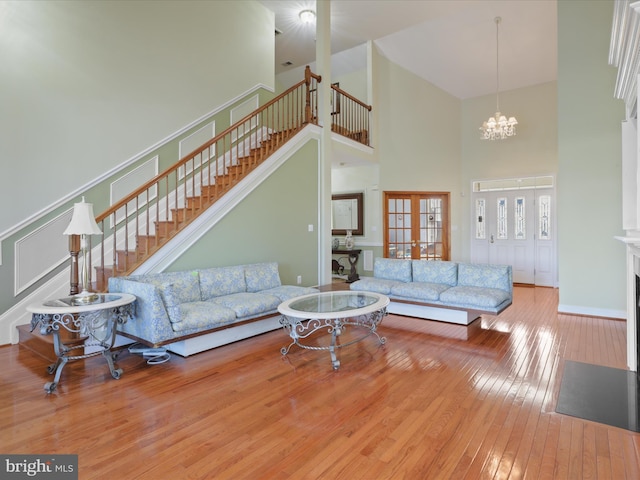 living room with a towering ceiling, hardwood / wood-style floors, and a notable chandelier