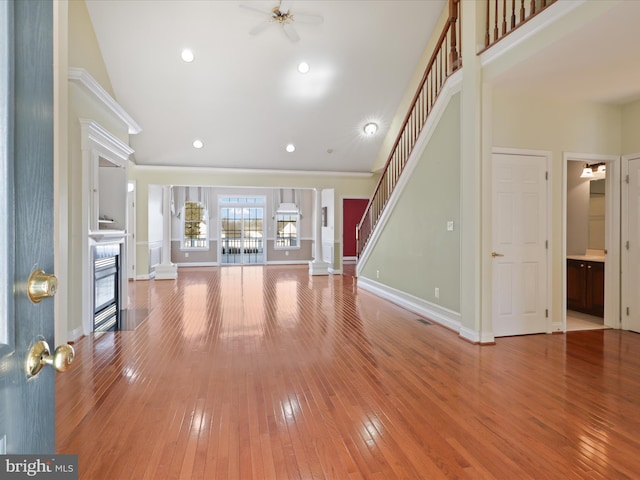 unfurnished living room featuring hardwood / wood-style floors, a towering ceiling, and ceiling fan