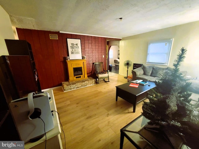 living room with light hardwood / wood-style floors, a textured ceiling, and wooden walls