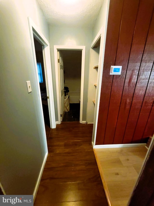 hall with a textured ceiling and dark hardwood / wood-style flooring