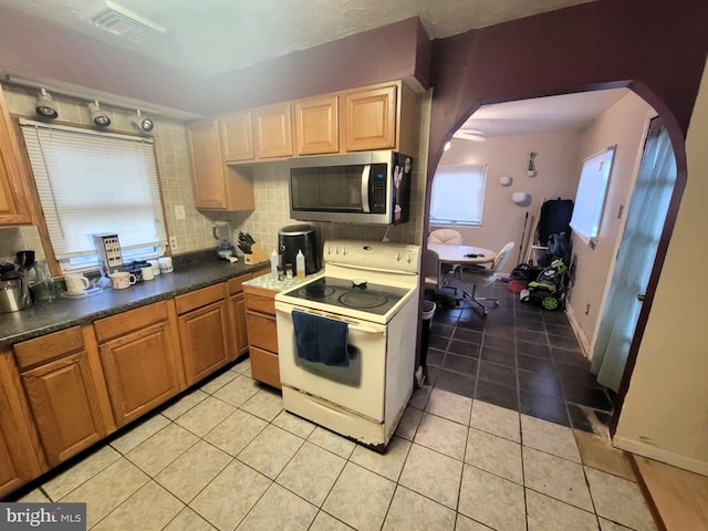 kitchen with white range with electric cooktop, light tile patterned floors, and backsplash