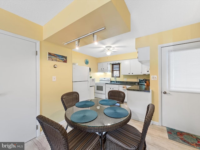 dining area with rail lighting, a textured ceiling, ceiling fan, sink, and light hardwood / wood-style floors