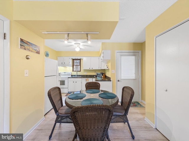 dining space featuring ceiling fan, sink, track lighting, and light wood-type flooring