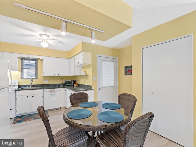 dining space with track lighting, a textured ceiling, ceiling fan, sink, and light hardwood / wood-style floors