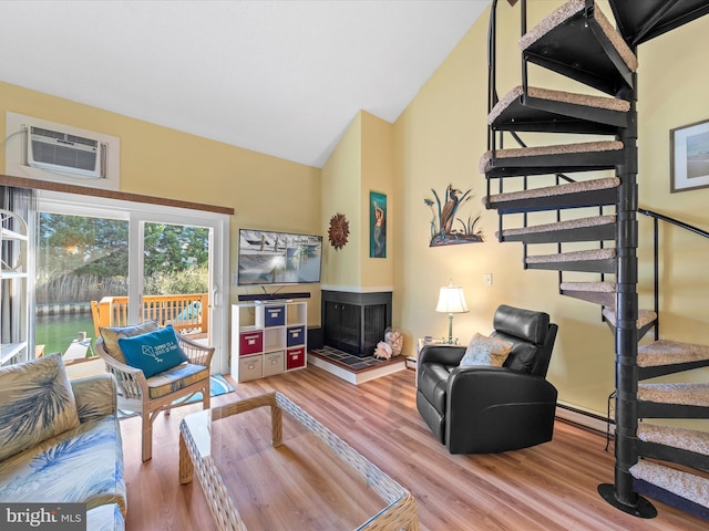 living room with a baseboard radiator, a wall mounted air conditioner, hardwood / wood-style floors, vaulted ceiling, and a tiled fireplace