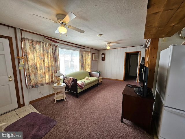 carpeted living room with a textured ceiling, ceiling fan, and wooden walls