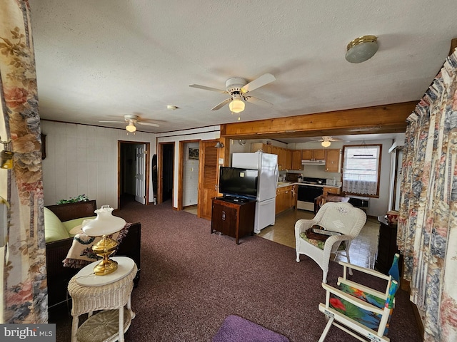 carpeted living room with ceiling fan, a textured ceiling, and wooden walls