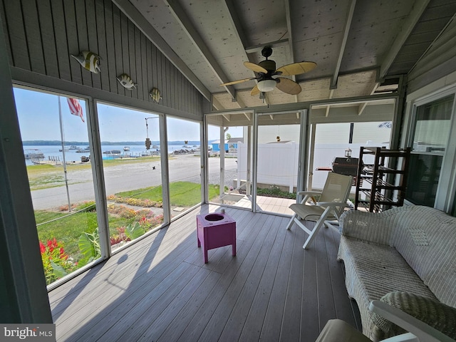 sunroom featuring a beach view, a water view, vaulted ceiling, and ceiling fan