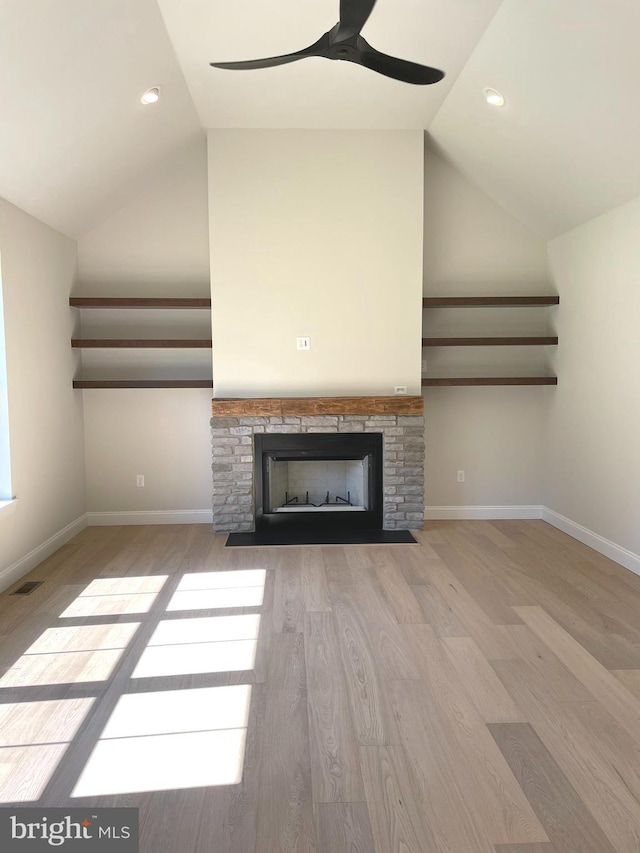 unfurnished living room featuring ceiling fan, light hardwood / wood-style floors, lofted ceiling, and a fireplace