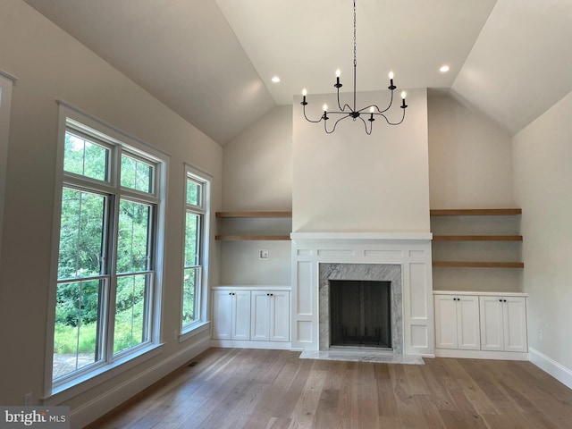 unfurnished living room with a high end fireplace, vaulted ceiling, and a wealth of natural light