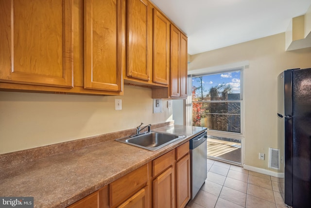 kitchen with dishwasher, black refrigerator, light tile patterned floors, and sink