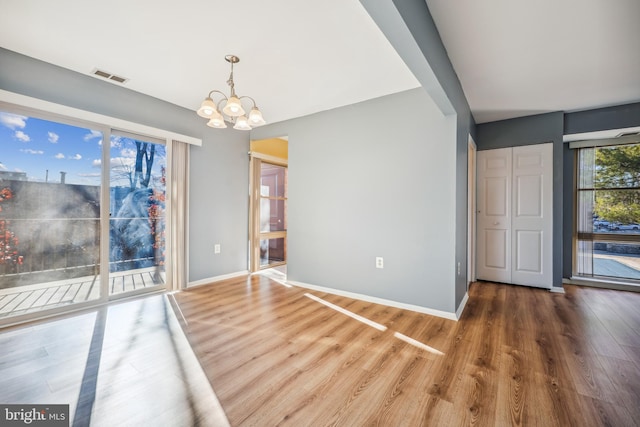 unfurnished dining area featuring hardwood / wood-style floors and an inviting chandelier