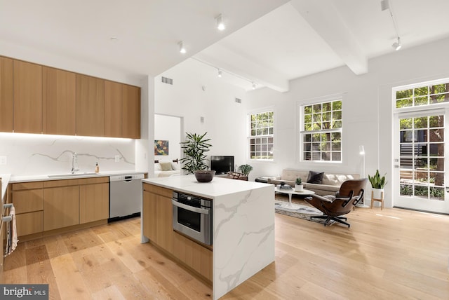 kitchen featuring a wealth of natural light, beam ceiling, sink, and appliances with stainless steel finishes