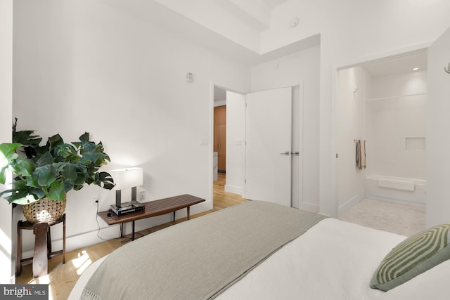 bedroom with light hardwood / wood-style floors and ensuite bath