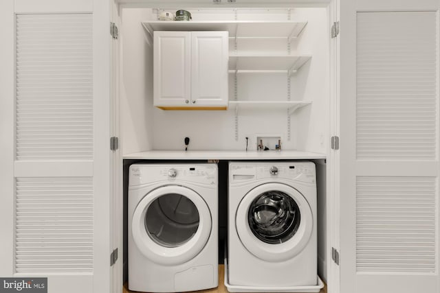 washroom with cabinets and washing machine and clothes dryer