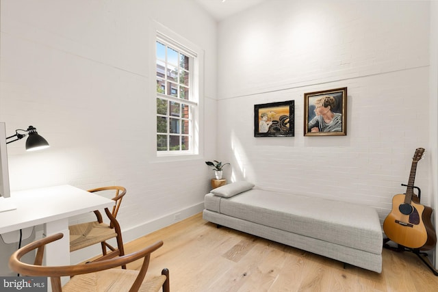 sitting room with light hardwood / wood-style floors and brick wall