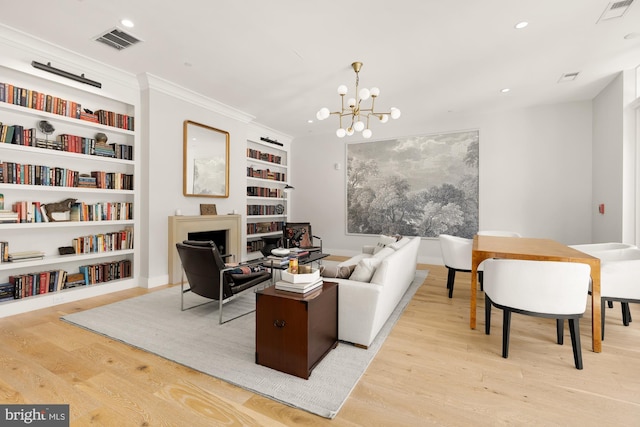 living room with crown molding, built in features, a chandelier, and light wood-type flooring