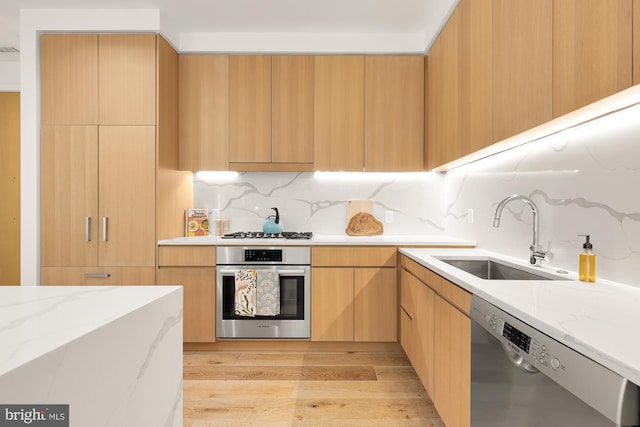 kitchen with sink, light brown cabinets, stainless steel appliances, light hardwood / wood-style flooring, and backsplash