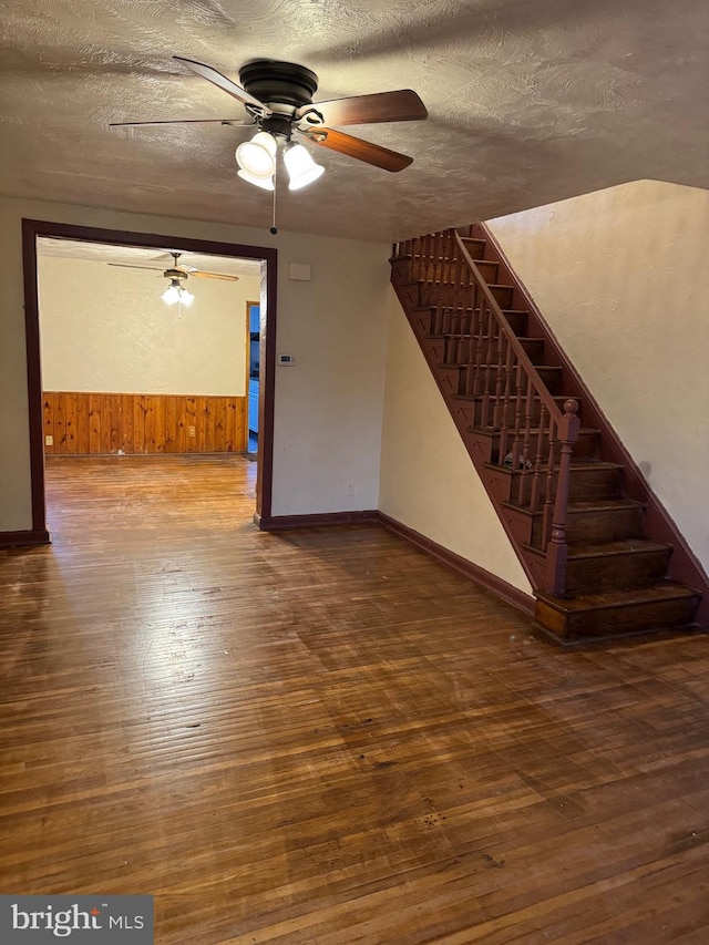 interior space with hardwood / wood-style floors, ceiling fan, a textured ceiling, and wooden walls