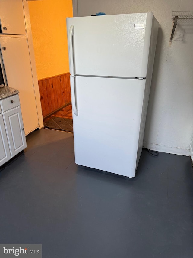 kitchen with white cabinets, white fridge, and wooden walls